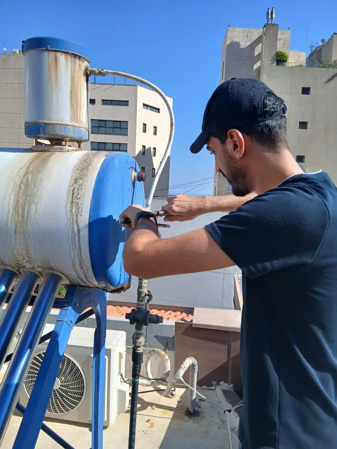 Technician servicing a rooftop water heater and tank